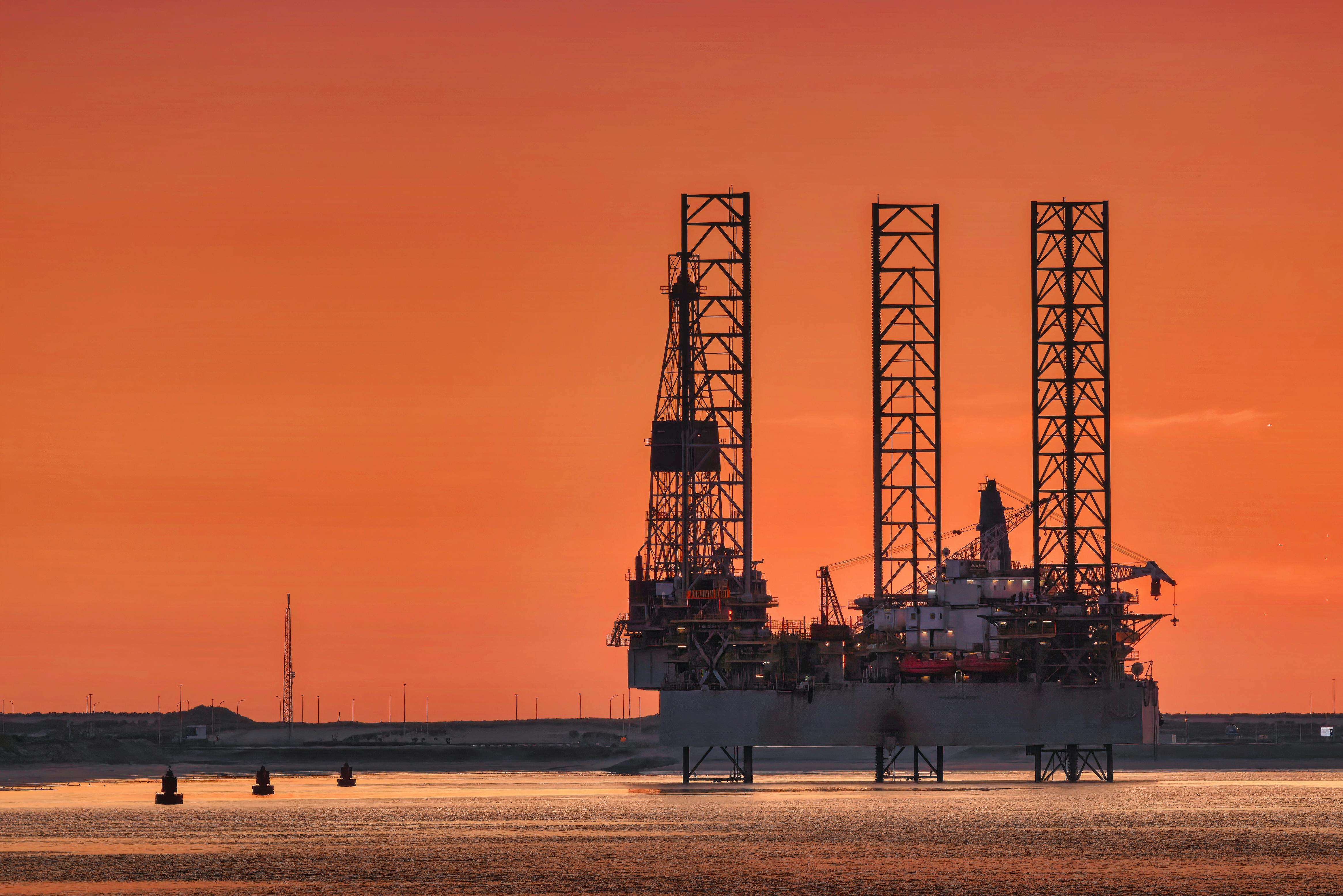 Oil pump jack in a field at sunset